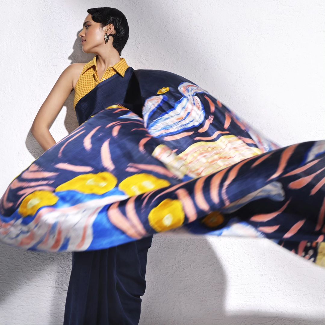 A celestial dreamscape of swirling brushstrokes and shimmering hues, this hand-painted Murshidabad silk saree pays tribu...